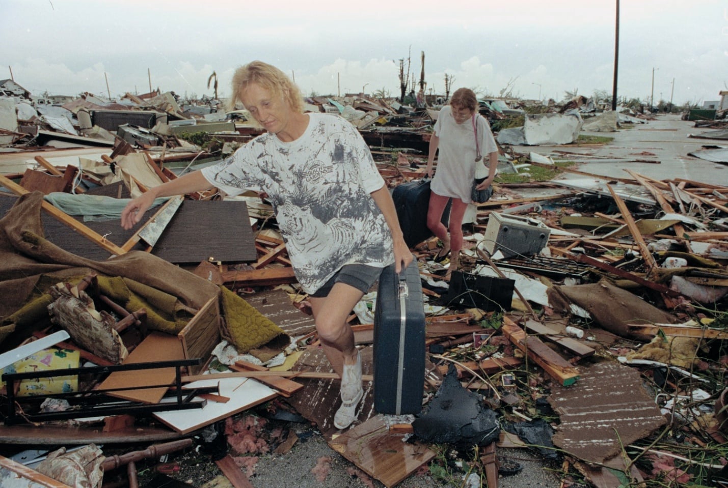 Nursery family members standing amid Hurricane Andrew debris